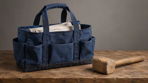 A blue canvas tool tote with folded plain cloth inside rests on a plain workbench beside a wooden mallet in raking light.
