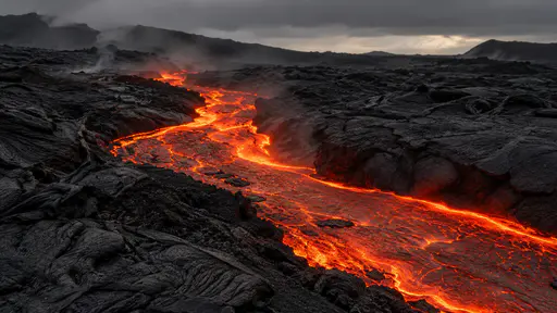 One bright molten lava channel runs in a glowing ribbon between two dark cooled banks across a black lava field in dim overcast light.