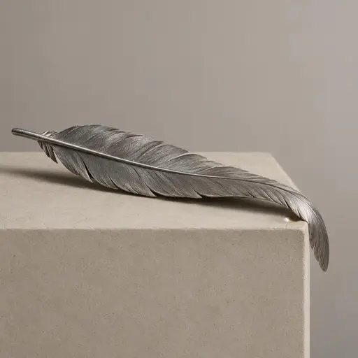 Diagonal dull brushed aluminium feather across a plain chalk block with its tip bending over the lower right edge, pressing one small bright burnished dent into the matte block top.