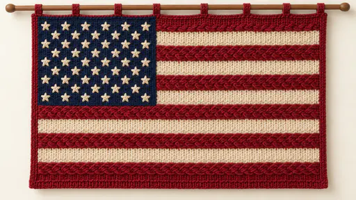 The American flag is knitted in thick cranberry red and cream wool stripes with a navy canton of small cream star loops, raised cable crossings, a ribbed hem and a wooden dowel on a pale ground.