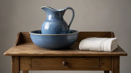 A blue ceramic jug stands inside its matching blue basin on a plain wooden washstand beside a folded plain towel.