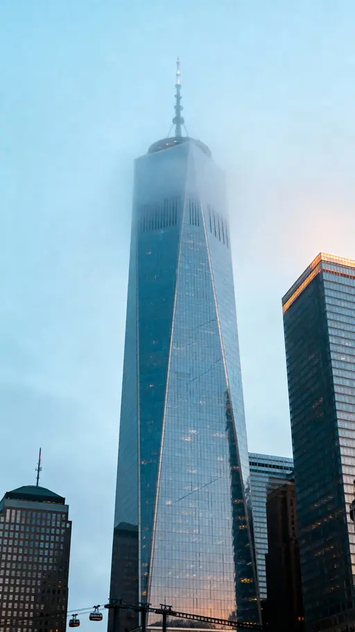 A vertical cinematic view of chrome skyscrapers rising through cool mist in a 9:16 frame, emphasizing reflective surfaces, layered depth, and a quiet futuristic mood for editorial or wallpaper use.
