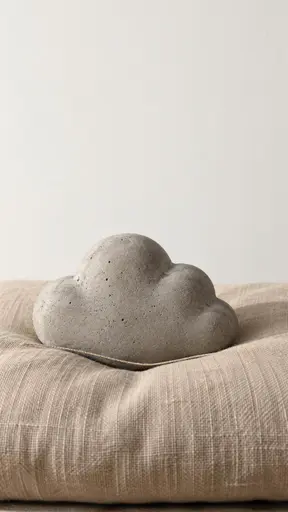 Still-life photograph of a small cement grey cast-concrete cloud resting on a thin warm linen cushion with a visible dent and soft contact shadow, a single loose thread pulled taut straight across the hollow against a blank off-white wall.