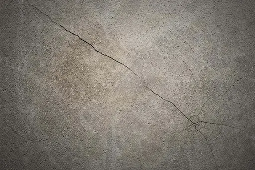Close-up abstract photograph of a rough concrete wall with subtle cracks and soft side lighting, composed for a 3:2 wallpaper or background image file.