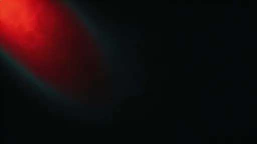 Widescreen 16:9 wallpaper showing an off-center deep crimson glow drifting diagonally into OLED-friendly near-black with ember highlights, a faint cyan-teal fringe, and soft bloom.