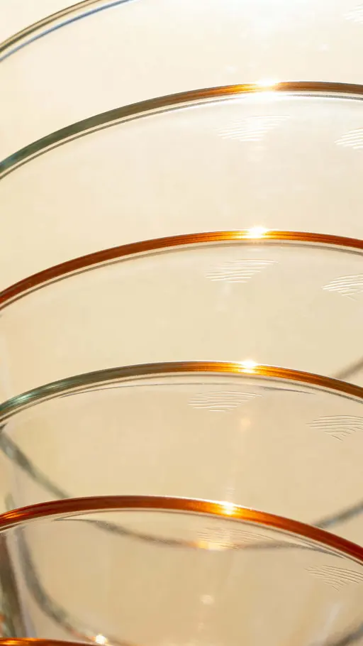 A cinematic macro study of curved transparent glass surfaces reflecting warm sunlight with smooth edges and bright minimalist framing, captured as an elegant vertical 9:16 crop for portrait display.