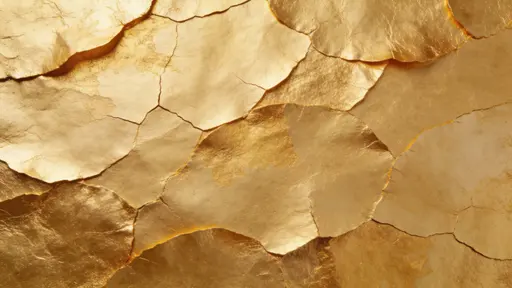 Flat full-frame gold leaf texture in 16:9 showing thin overlapping layers with visible seams and gentle cracking, an organic artisanal surface with subtle tonal shifts in warm golds.