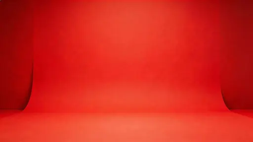 Widescreen 16:9 studio product shot of a matte-red seamless paper backdrop with a smooth sweep, gentle floor-to-wall curve, soft diffusion and subtle falloff.