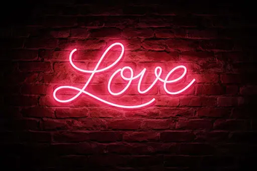 Cinematic 3:2 night photograph of a glowing pink neon 'LOVE' cursive glass sign centered on a weathered red brick wall, casting warm romantic light.