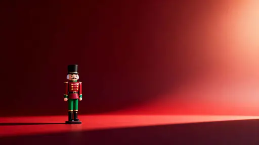 A wide 16:9 Christmas scene shows a single nutcracker figure on the left wearing a deep red uniform with green accents and gold buttons against a dark red gradient background.