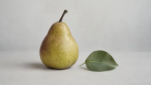 One ripe whole pear with its stem rests on a plain pale surface beside one plain green leaf in soft even light.