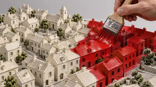 Painting the town red: a high three-quarter miniature architectural photograph under soft studio light, where a broad paintbrush held in a giant hand lays a single continuous wet red stroke across the roofs and walls of several pale cream model buildings in a miniature town, the town ahead of…