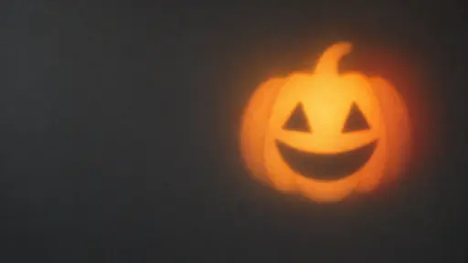 A pumpkin-shaped patch of soft amber light with the darker voids of a carved face sits just right of center on an empty charcoal studio wall, cast by no visible source. The undisturbed left half of the wall is clean copy space, a minimal Halloween background with generous negative space for seasonal text or headings.