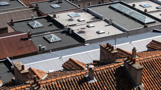 Aerial architectural photograph of urban rooftops framed in a 16:9 ratio, emphasizing geometric roofs, vents, skylights and textures with a clean overhead composition for wallpaper.