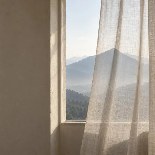 A side window holds a hazy stone-blue mountain view behind a loosely hanging translucent linen curtain whose single aligned fold continues one sharp distant ridgeline while its soft shadow extends a second fainter ridge, every other fold plainly mismatching.