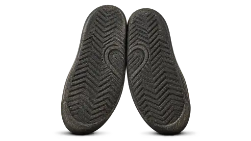 Sole mates: Two worn rubber shoe soles stand upright leaning toward each other, their facing tread edges touching so the grooves form two mirrored halves of one heart outline between them, each sole resting on a soft shadow, isolated on a transparent background in warm product light.