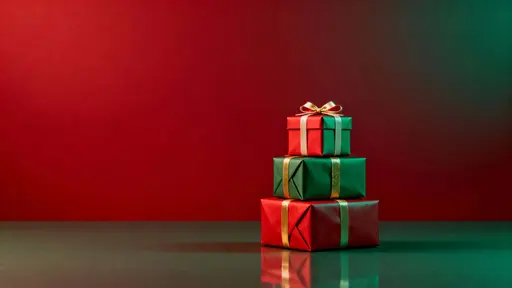 Horizontal Christmas scene with a small tower of red, green and gold wrapped gift boxes stacked slightly right of center on a subtle reflective surface, leaving calm copy space above and left.