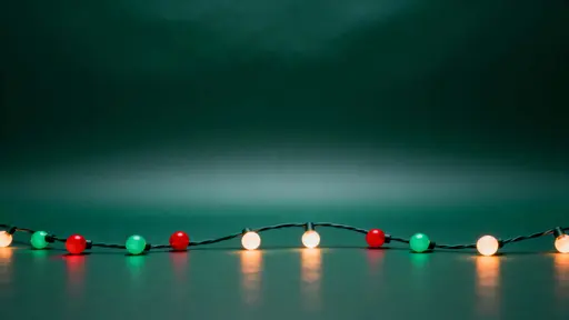 A 16:9 Christmas background with a deep pine-green gradient, a gentle arc of small round red, green, and warm-white bulbs on a subtle dark cable along the lower third, leaving a clear upper area for copy.