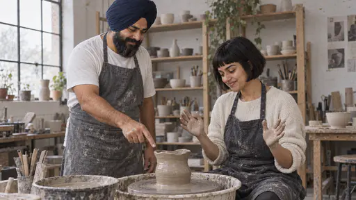 A broad bearded man in a navy turban reaches a calm hand toward a lopsided wet pot on the wheel head and points gently at its wobbling rim while a young woman with a short black bob sits at the wheel with her hands lifted off the clay and a rueful smile in soft light.