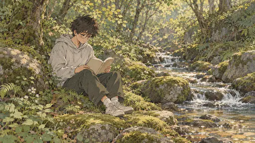 A teenage boy with round glasses and a grey hoodie sits on a mossy forest floor beside a stream reading an open paper book in dappled sunlight.