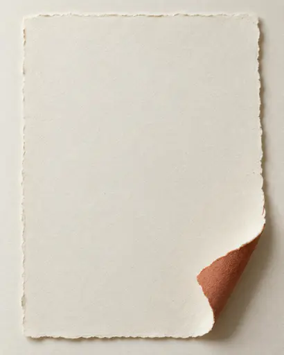 One thick ivory sheet on a textured pale surface curls at lower right, showing a terracotta reverse and a soft cast shadow.