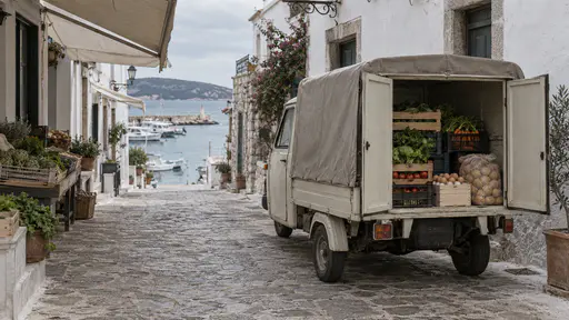 A small three-wheeled delivery van with a covered back stands in a narrow market street at midday with its rear doors open showing neat stacks of vegetable crates, a crate of eggs and a bag of potatoes under awnings, with no one in the street.