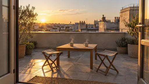 A tiny roof terrace holds a low plain table with two steaming cups and two folding stools beside a parapet wall in golden light.