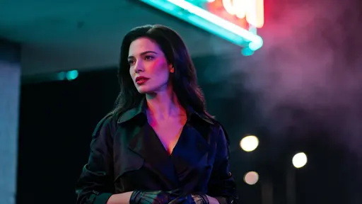 A widescreen 16:9 cinematic street scene of a woman in her early 30s standing on the left third under teal and electric magenta neon, rim-lit with soft mist and bokeh, high-contrast and crisp.